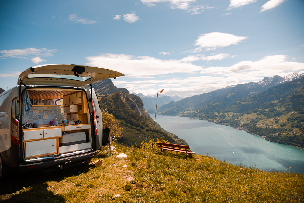 Imagem mostrando o interior de um van motorhome e um montanha de fundo